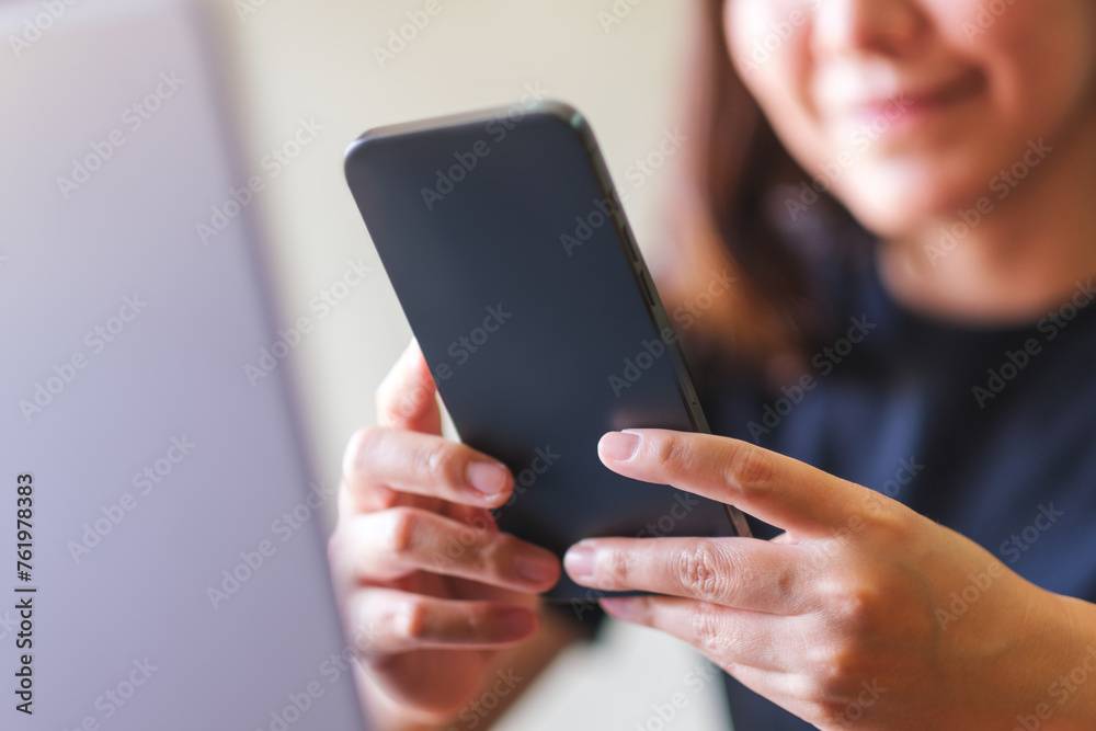 Closeup image of a young woman using smart phone and laptop computer Closeup image of a young woman using smart phone and laptop computer