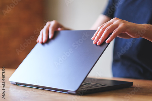 A woman opening or closing laptop computer, getting ready for work