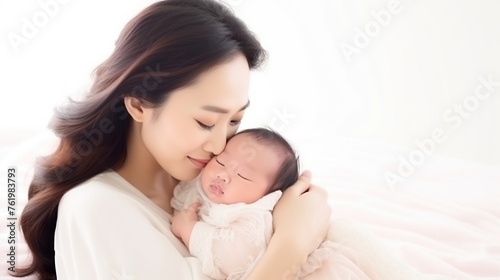 an Asian mother holding her newborn baby on a white background
