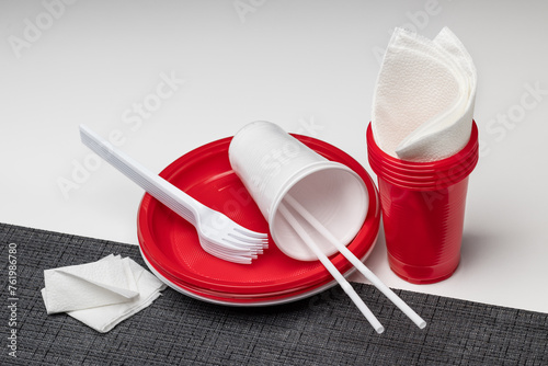 Disposable colored dishes on a dark napkin, a white background. Plastic processing.