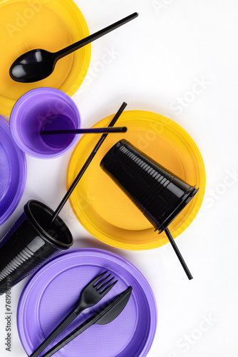 A set of disposable plastic tableware in lilac, yellow and black colors. Ecology and plastic waste recycling concept