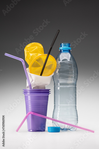 Used plastic. Disposable cups, drinking straws and a bottle. The concept of ecology and recycling.