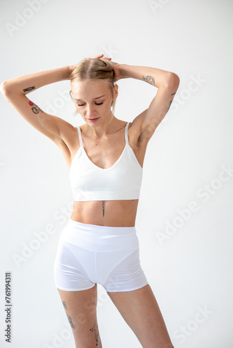 Blonde girl posing on a white background in a top and leggings