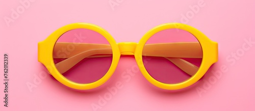 Yellow sunglasses on pink background photo