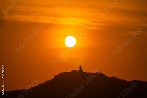 The sun circles in the red sky above Phuket Big Buddha..Amazing Phuket big Buddha in circle of the sun in red sky..The beauty of the statue fits perfectly with the charming nature. red sky background