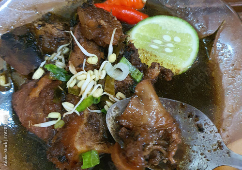 Rawon is an Indonesian beef soup. Originating from East Java, rawon utilizes the black keluak nut as the main seasoning, which gives a dark color and nutty flavor to the soup. photo