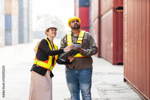 Caucasian woman supervisor and Indian man industrial worker work with tablet at a container yard. Shipping business management and international goods import-export. Concept of Logistic operation.