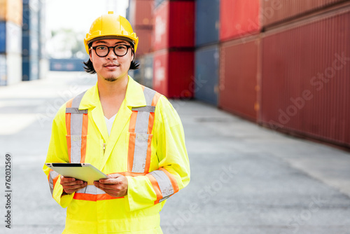 Portrait of Asian man engineer working with tablet at containers works at a container yard. Shipping business management and international goods import-export. Concept of Logistic operation. Diversity