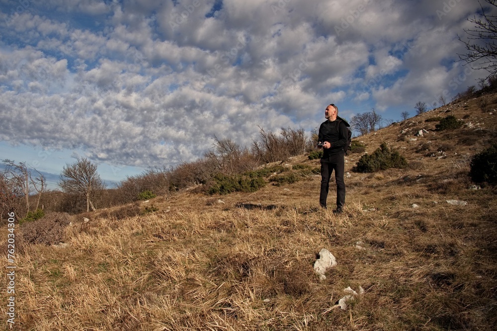 Mature man piloting drone on the mountain ridge Mature man piloting drone on the mountain ridge