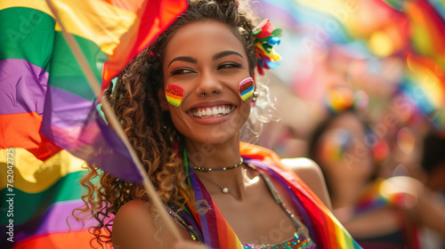 A joyful woman clad in a rainbow outfit proudly holds a rainbow flag high in the air