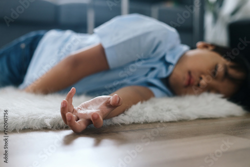 Little boy lying on the floor at home. Healthcare and medical concept. photo