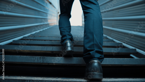 Closeup image of successful business man leg walking up to stair. Project manager changing workplace, discover a new thing, growth or getting promotion or walking in to light. Rising up. Exultant.