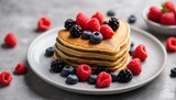 A scrumptious stack of golden pancakes adorned with a variety of fresh berries