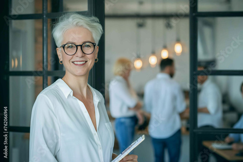 elegant senior businesswoman with short silver hair and glasses, smiling. 