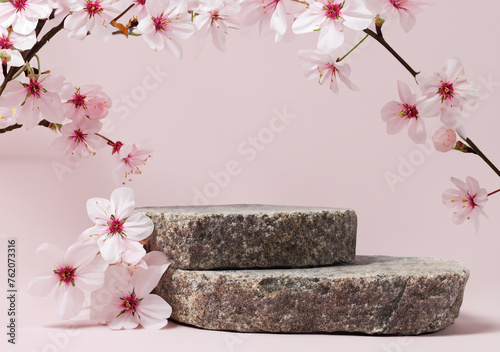 Podium or pedestal from nature stone decorated with cherry blossom twigs. Cosmetic mock up.