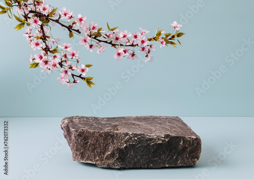 Podium or pedestal from nature stone decorated with cherry blossom twigs. Cosmetic mock up.
