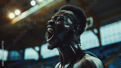 Basketball player celebrates victory. Screams with joy. Basketball stadium in the background. 