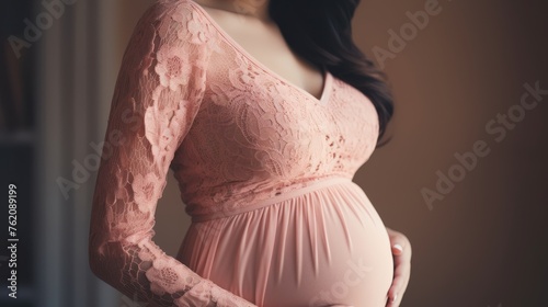 Pregnancy background - Closeup of pretty young pregnant woman with pregnancy belly, in soft elegance pink textile clothes