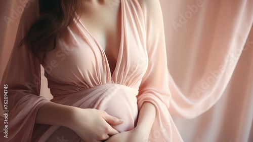 Pretty pregnant woman in soft pink maternity clothes, closeup pregnancy background