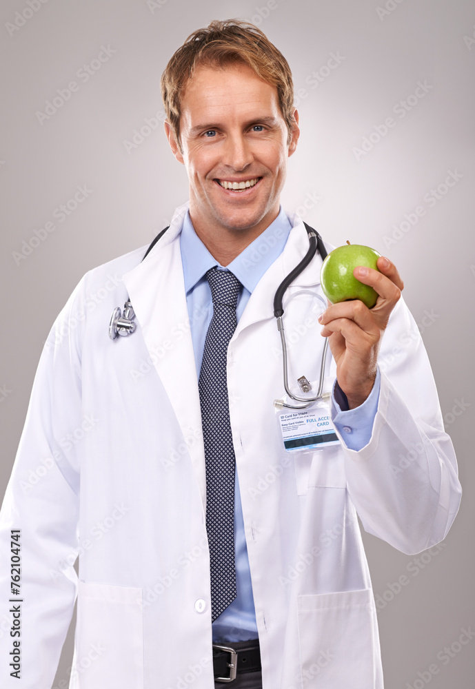Man, doctor and apple in studio portrait, medical expert and dietician on gray background. Happy male person, fruit and proud of choice or decision for nutrition, vitamins and minerals for health Man, doctor and apple in studio portrait, medical expert and dietician on gray background. Happy male person, fruit and proud of choice or decision for nutrition, vitamins and minerals for health