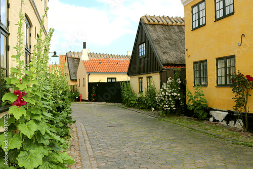 Quiet village cobbled street, historic, yellow painted houses with thatched and tiled roofs.