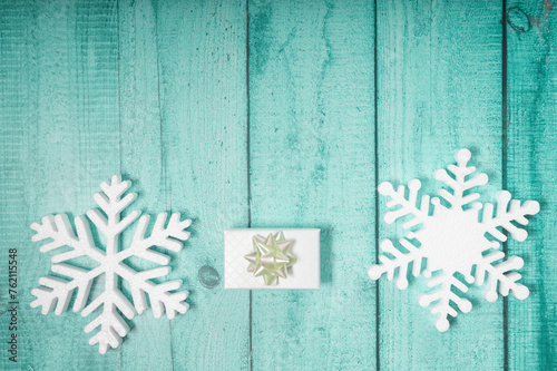 Snowflakes and present with ribbon on a blue wooden background. Christmas winter flatlay with copyspace