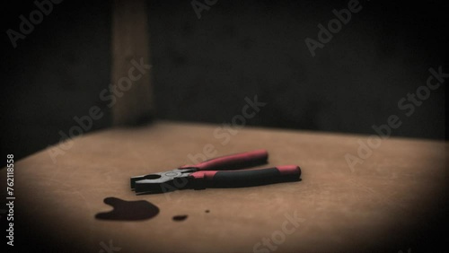 High quality, close-up shot of a pair of bloody pliers on a chair in a sinister interrogation torture chamber, with dark creepy grungy walls, blood on the floor, under a spotlight photo