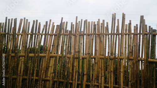 Traditional fence made for bamboo against gray sky, textured background