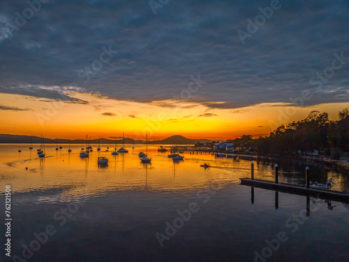 Aerial sunrise over the water with boats and clouds © Merrillie