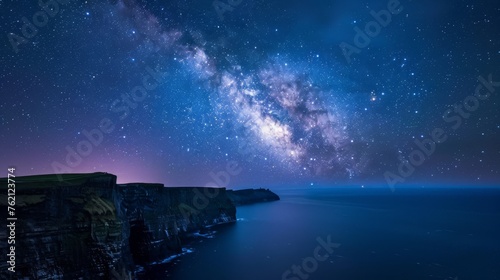 Milky Way galaxy over a dramatic cliff coastline, reflecting in the ocean below under a starry sky. © Moopingz