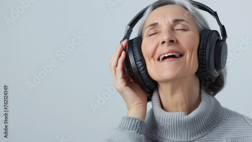 A serene senior woman lost in music with eyes closed and headphones on.