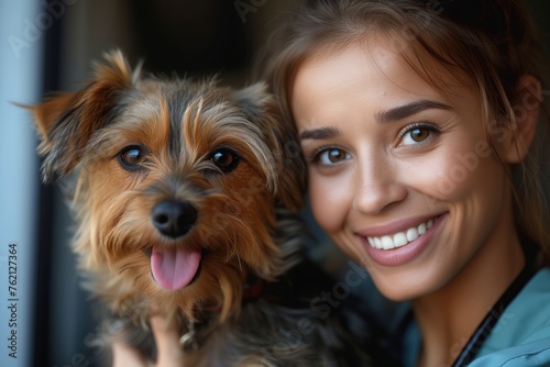 A young woman smiling warmly as she holds a happy Yorkshire Terrier close to her
