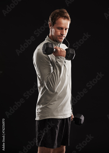 Man, dumbbells and weightlifting exercise in studio or fitness performance, training or black background. Male person, equipment and earphones for music playlist or healthy, streaming or mockup space