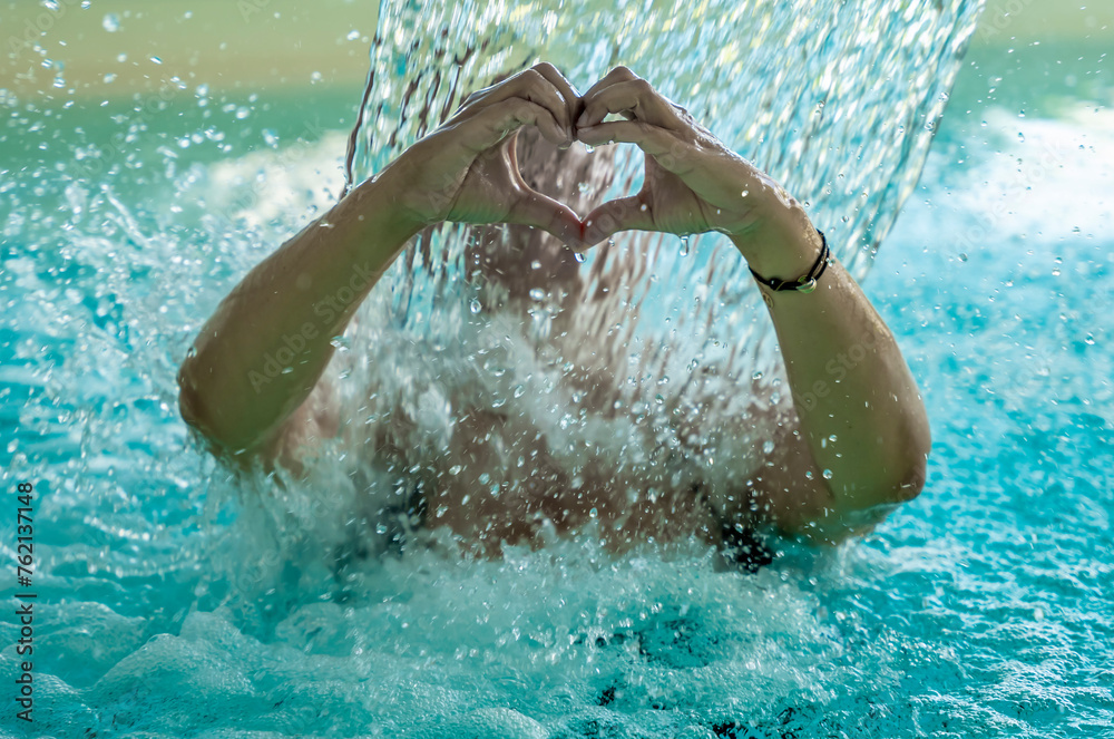 Woman Making a Heart Shape with Her Hands in a Hydromassage Pool with Falling Water in Switzerland.