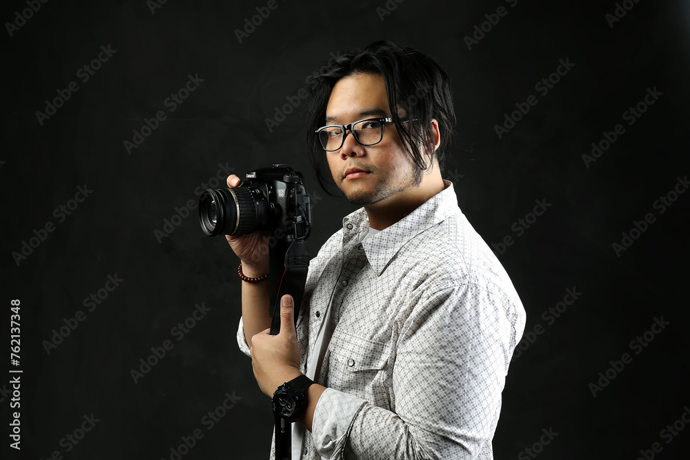 portrait of a photographer with his digital camera on a dark background portrait of a photographer with his digital camera on a dark background