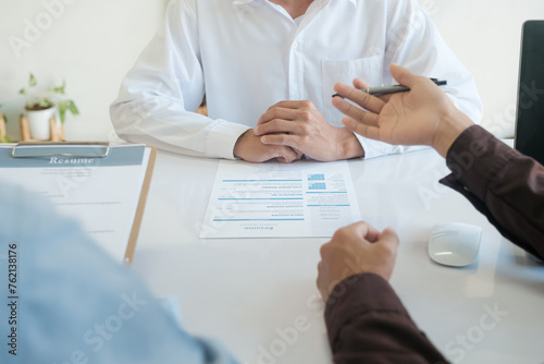 Three people are sitting at a table with a resume in front of them
