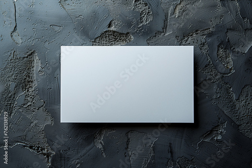 A blank white card rests against a black concrete background photo