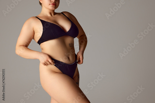 Woman, model plus size in dark lingerie, showcasing natural body curves against grey studio background. Concept of natural beauty, femininity, body positivity, wellness, spa procedures. © Lustre