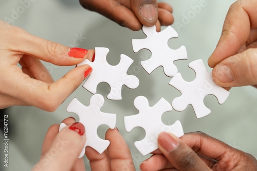 Multi-ethnic hands - assembling puzzle - symbol of teamwork and solutions, collaboration and problem-solving - finding common solution concept