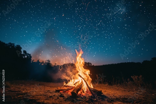 A campfire with rising smoke under the clear night sky filled with stars