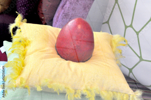 Osterdekoration: Ein rotes Osterei auf gelben Kissen im Schaufenster.