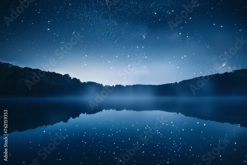 Starry night sky reflected in a serene lake with wisps of fog and smoke above the water
