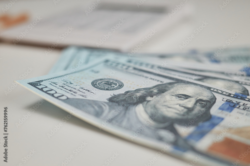 Money-saving. Dollar bill organization in business. One hundred dollar bills on table top with pencil and calculator on background American currency patterns Money-saving. Dollar bill organization in business. One hundred dollar bills on table top with pencil and calculator on background American currency patterns