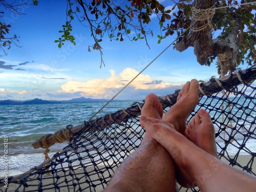 persons relaxing on a beach hammock photo