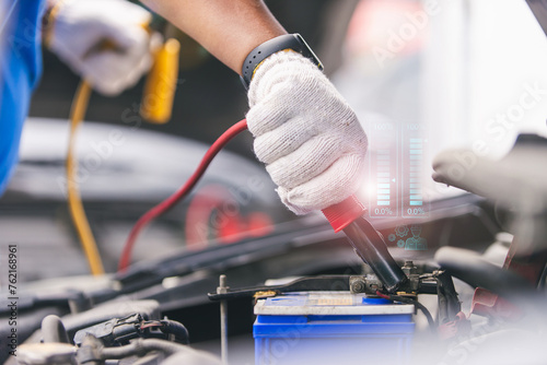 a mechanic using jumper cables to manually power a car's battery