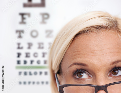 Woman, glasses and reading of chart for eye test, wellness and frame in closeup. Person or ophthalmologist .looking up, thinking and ideas for optometry, vision and lens check or exam and assessment