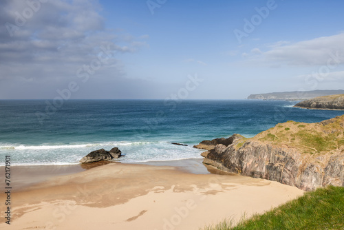 The unspoiled charm of Durness Beach, Scotland, is evident in the gentle embrace of azure waters against the pristine sandy shore