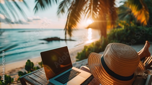 Remote work concept with a person using a laptop on a tropical beach at sunset, embodying a work-life balance.