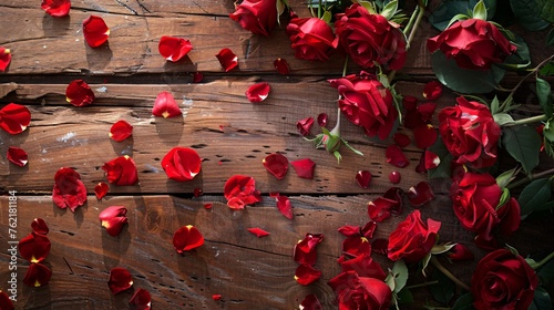 a wooden table with scattered rose petals and red roses