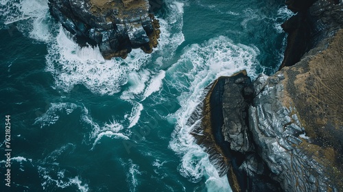 Drone shot of the powerful waves crashing against a rugged cliff, showcasing the dramatic interaction between rock and sea. Aerial View of Rocky Cliff and Turbulent Sea